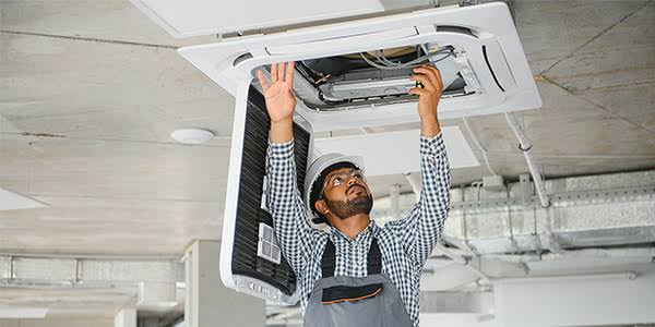 Technician working on a ceiling-mounted air conditioning cassette